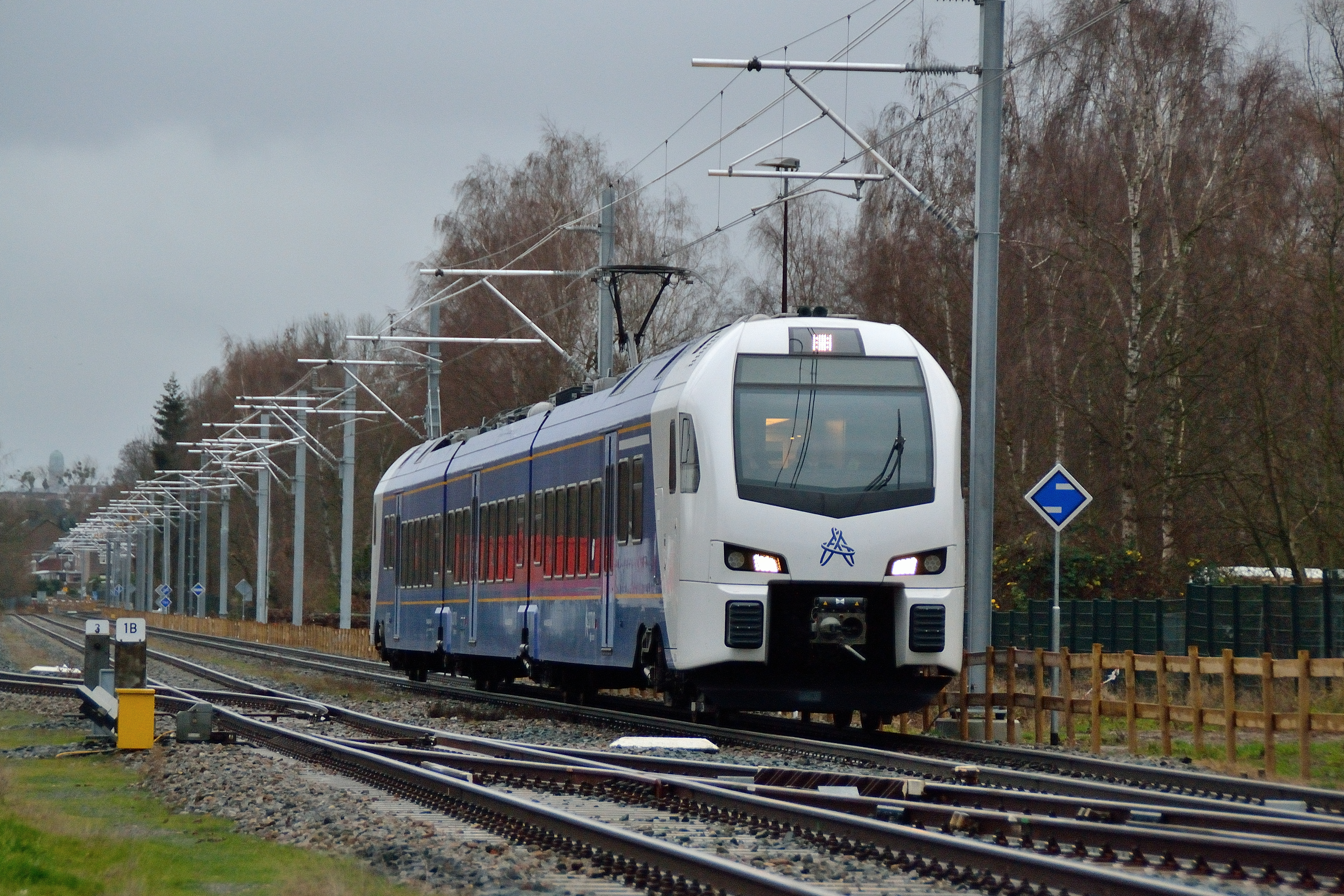 Trein van Arriva rijdt over spoor op een bewolkte winterdag.